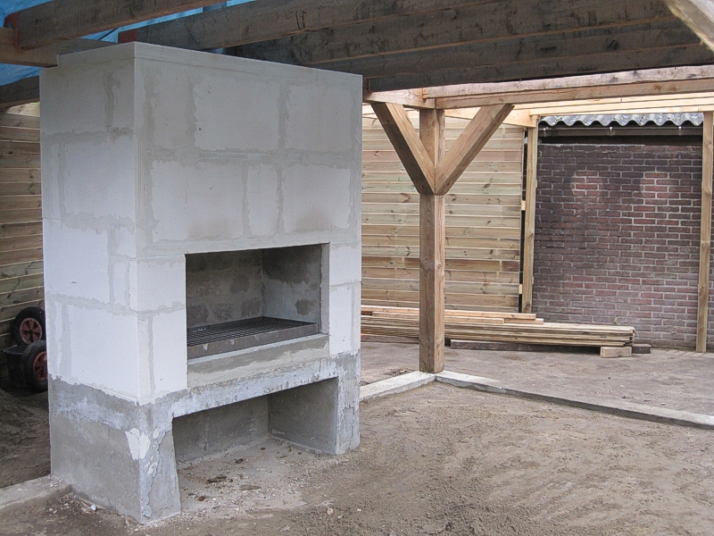 Gemetselde buitenhaard onder een houten veranda in aanbouw