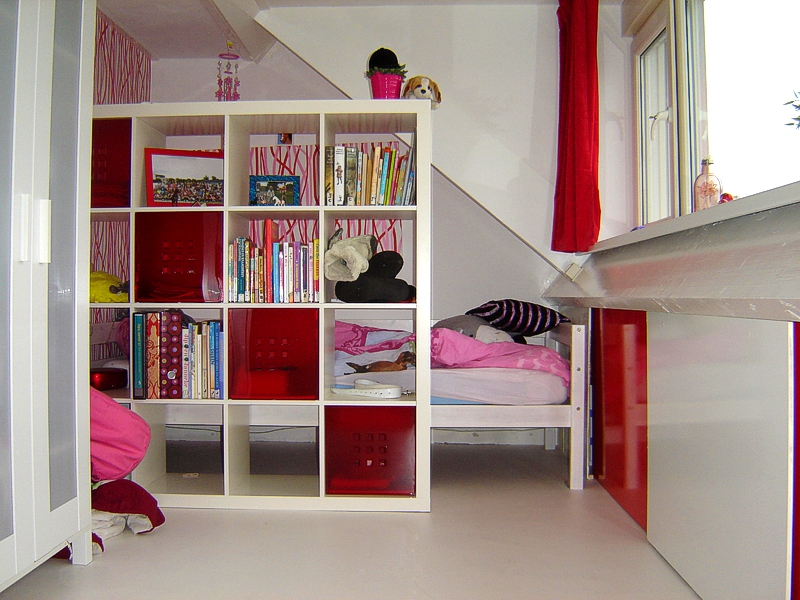 Slaapkamer onder het dak met open boekenkast en rood-witte inbouwkasten